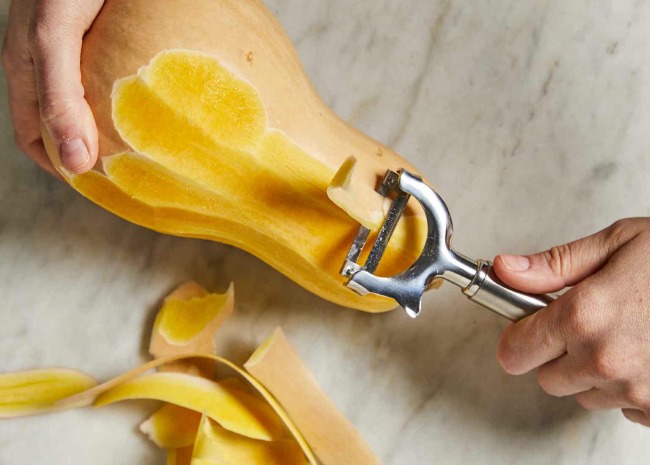 peeling butternut squash with a vegetable peeler